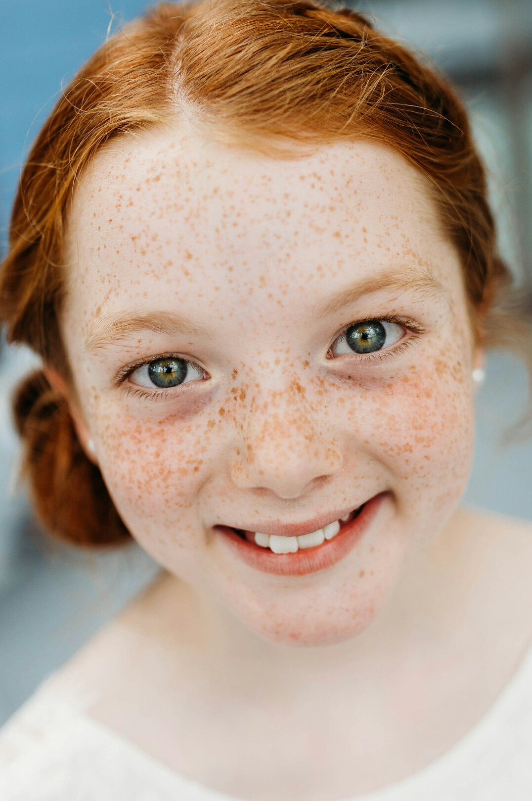 Portrait of a woman with red hair and freckles smiling at the camera