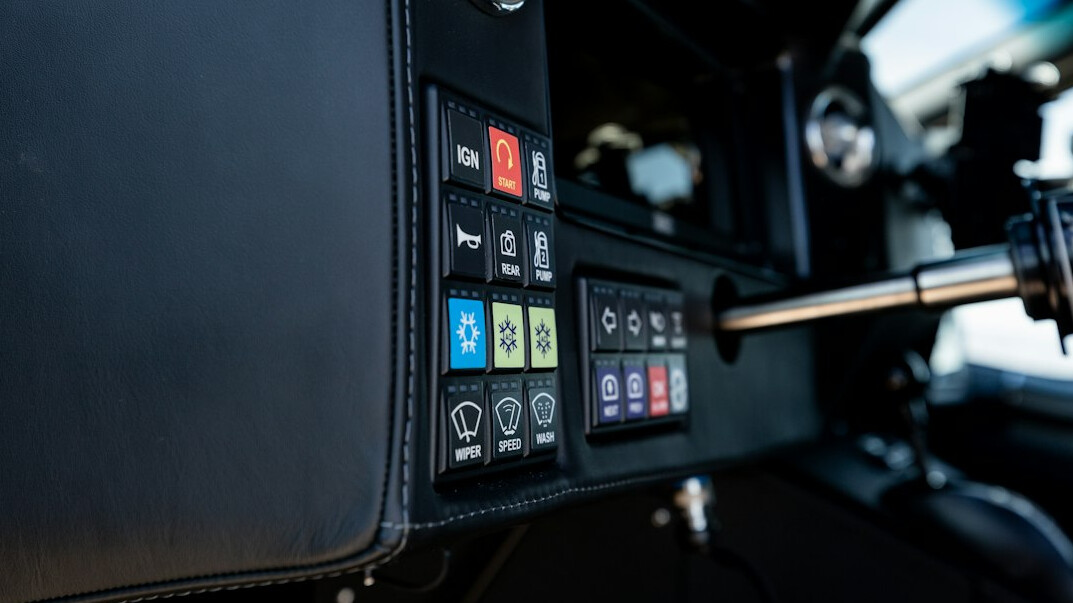 Close-up of a broadcast vision mixer panel with illuminated buttons and a multiview monitor