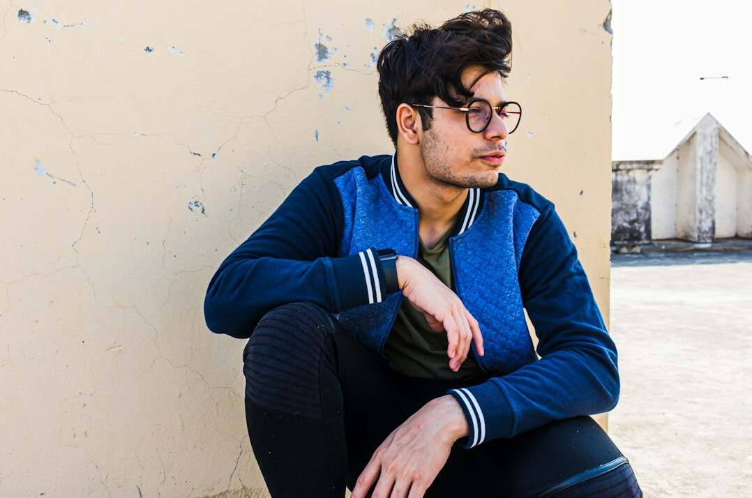Portrait of a man with short hair and glasses wearing a navy jacket