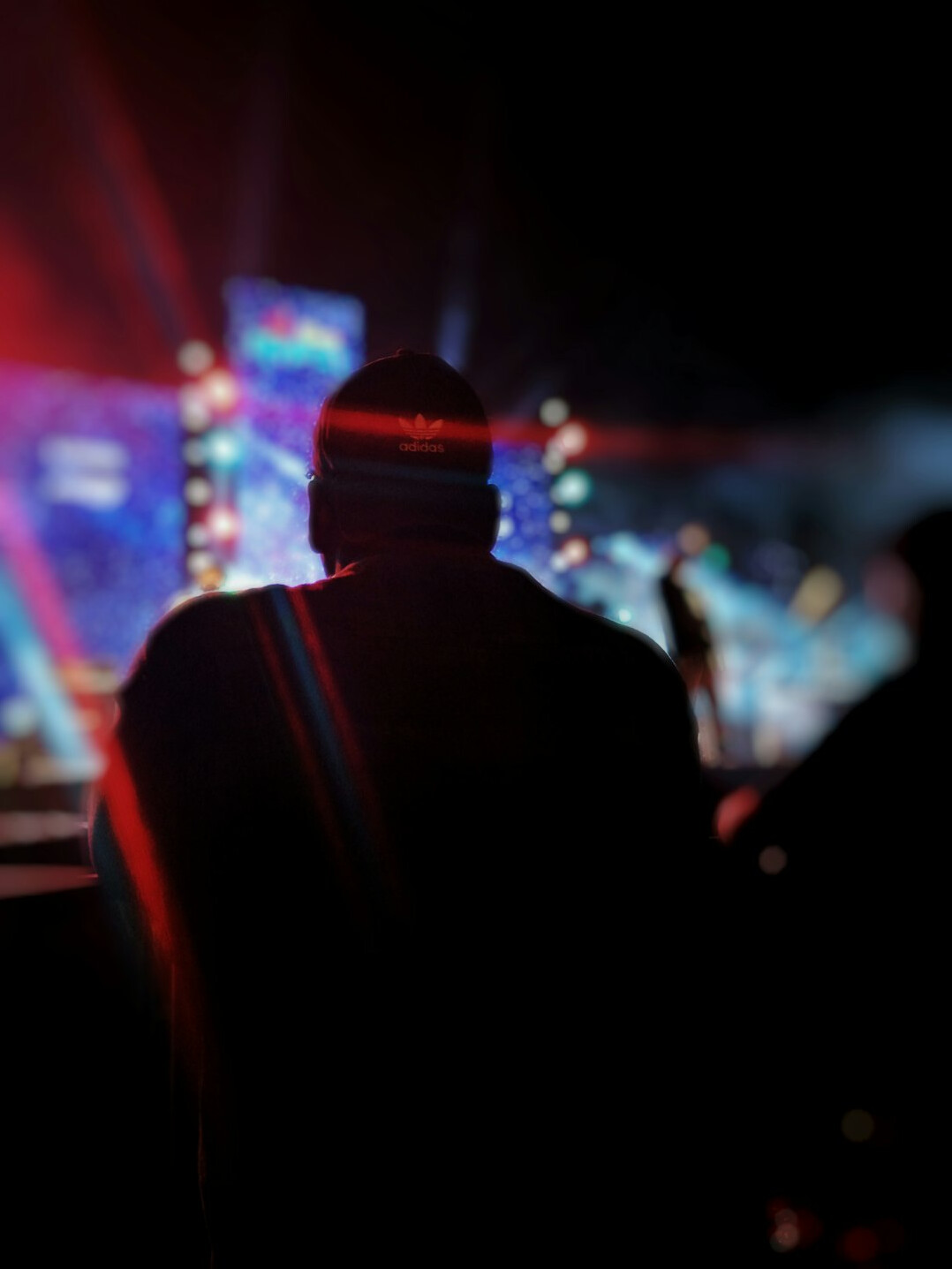 Vision mixer operator seen from behind in front of a bright wall of monitors
